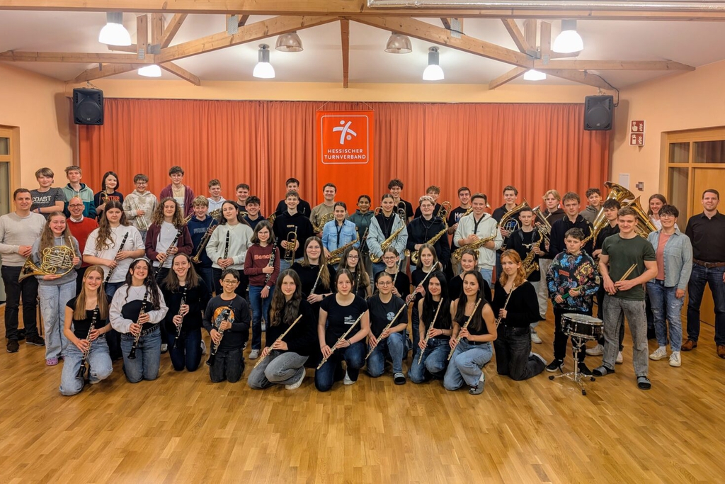 Eine Gruppe an Menschen posiert mit ihren Instrumenten für ein Foto.