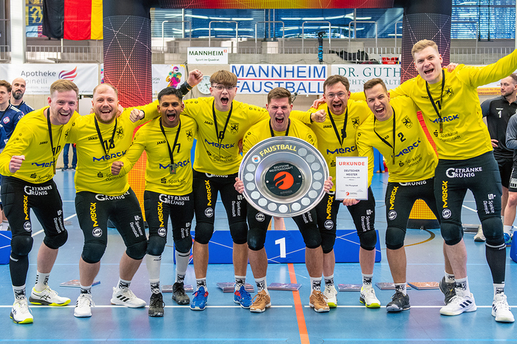 Die Mannschaft steht mit der Siegerschale dicht zusammen und jubelt zur Kamera