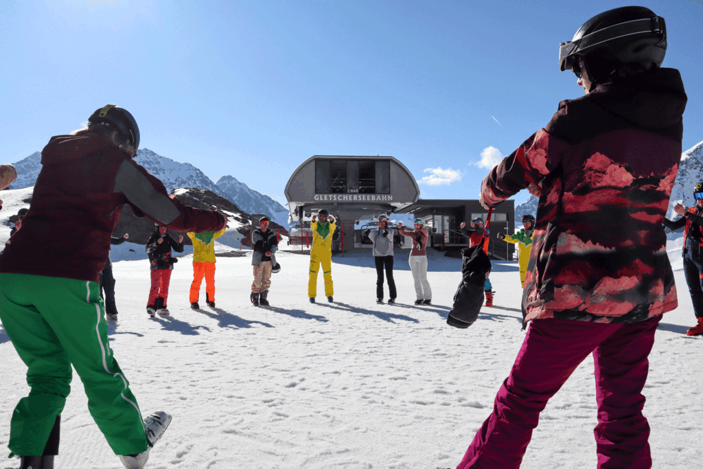 Eine Gruppe von Skifahrer*innen dehnen sich zusammen auf der Piste.