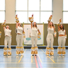 Ein Mädchengruppe tanzt in einer Sporthalle.