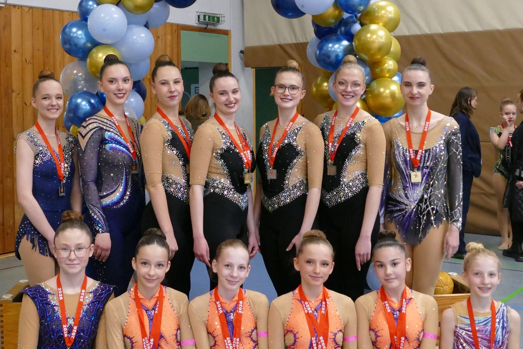 Mehrere Gymnastinnen posieren mit Medaillen.