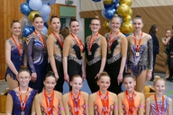 Mehrere Gymnastinnen posieren mit Medaillen.