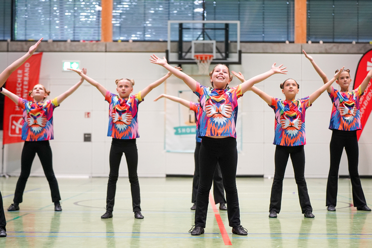 Eine Gruppe junger Mädchen präsentiert in bunten Kostümen eine Show.