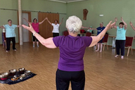 Mehrere Frauen machen gemeinsam QiGong-Übungen in einem Gymnastikraum