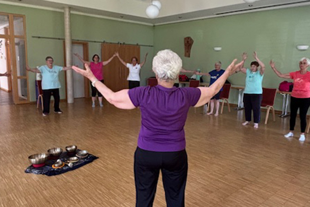 Mehrere Frauen machen gemeinsam QiGong-Übungen in einem Gymnastikraum