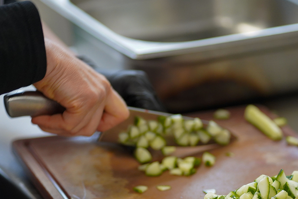 Ein Koch schneidet Gemüse auf einem Brettchen.
