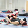 Eine Frau liegt mit dem Rücken auf einer Gymnastikmatte und macht eine Dehnübung.