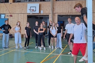 Eine Gruppe schaut auf einen Trainer der eine Übung erklärt.