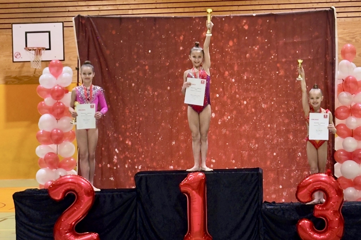 Drei Sportlerinnen stehen bei einer Siegerehrung auf einem Podest.