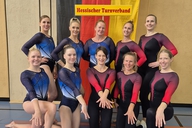 Ein Team aus 10 Turnerinnen posiert für ein Foto.