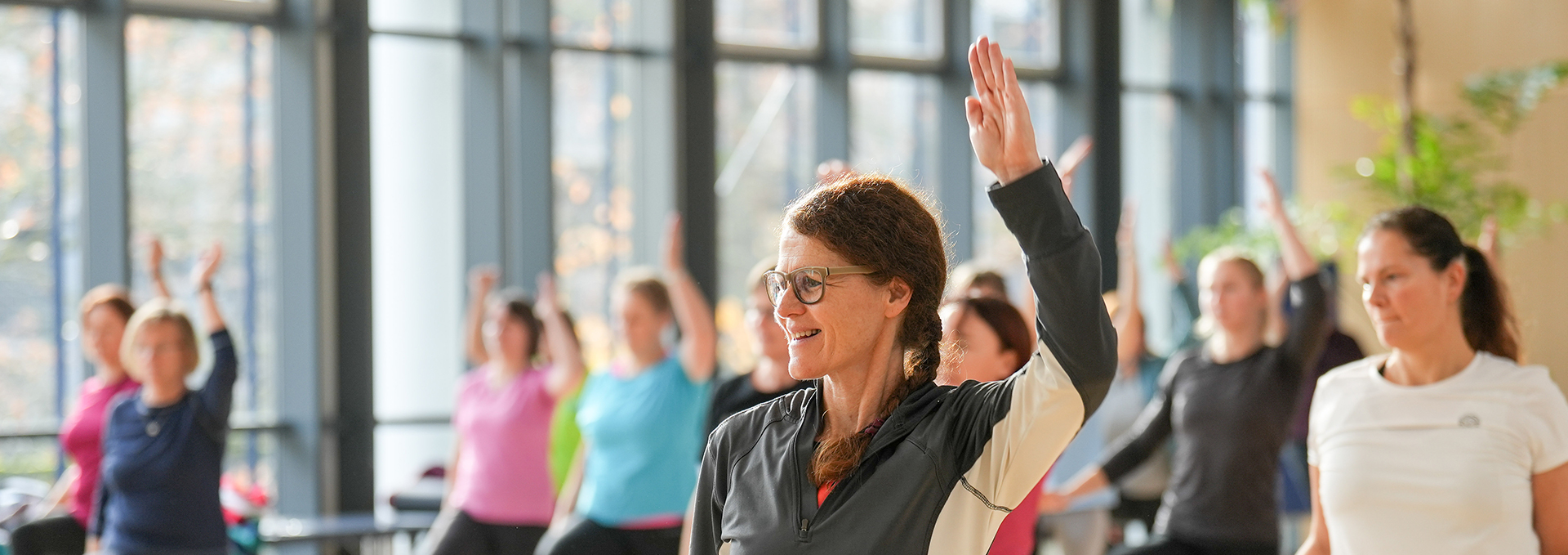 Eine Frau in Sportkleidung hebt die Hand. 