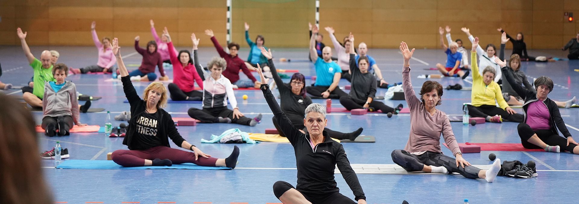 Eine Gruppe von Personen macht eine Dehnübung auf Matten.