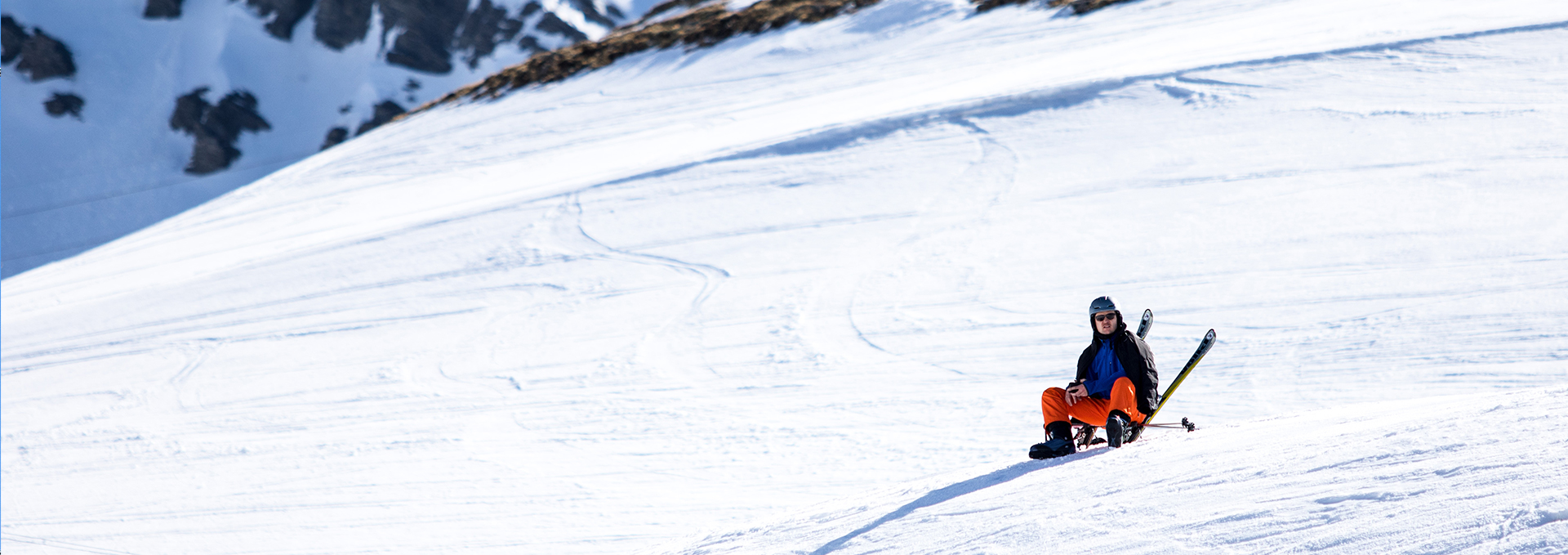 Ein Mann fährt mit einem Schlitten eine schneebedeckte Piste runter.