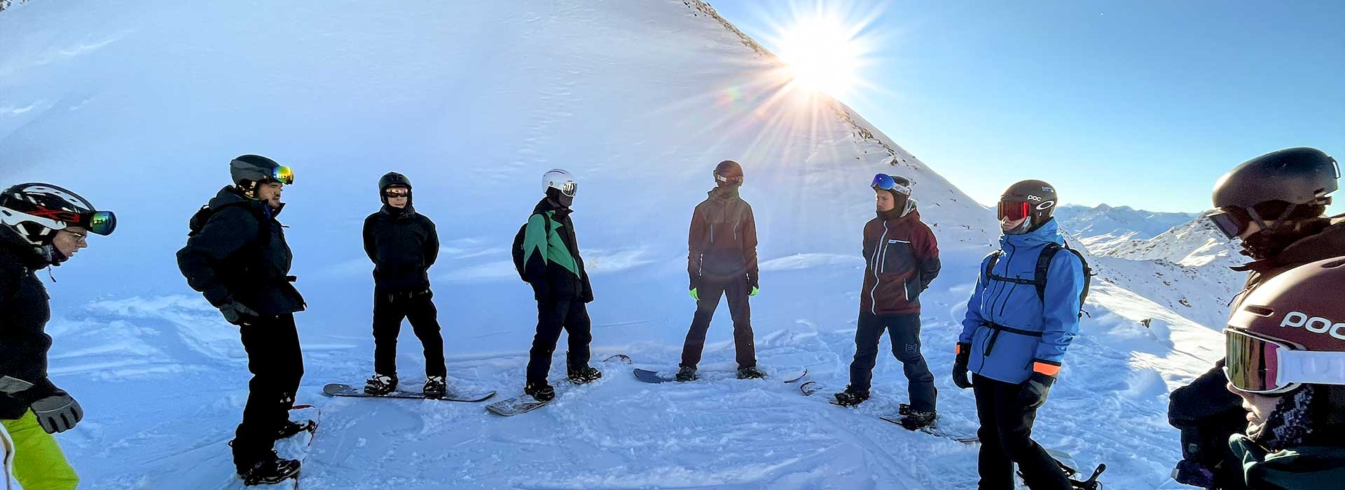 Eine Gruppe Snowboarder steht in einem Kreis im Schnee.