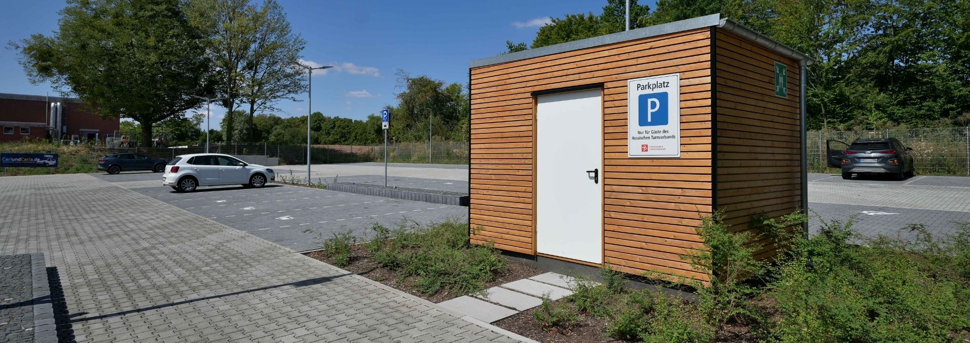 Ein Parkplatz für Autos mit einem Häusschen.
