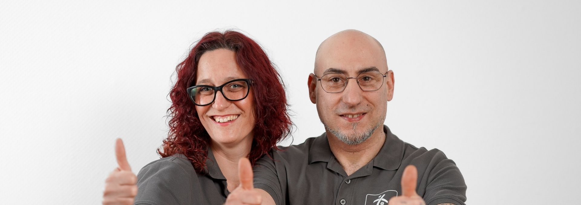 Zwei Personen lächeln und zeigen die Daumen hoch.
