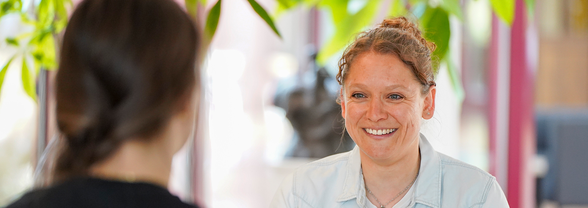 Zwei Frauen sitzen sich gegenüber und sprechen lachend miteinander.