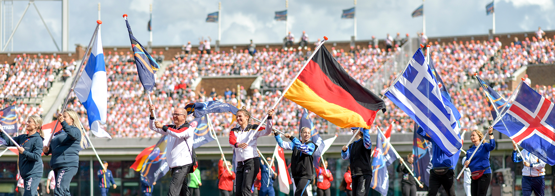 Mehrere Menschen tragen ihre Nationalflaggen durch ein Stadion.