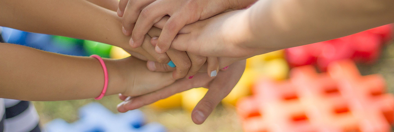 Kinder halten ihre Hände übereinander.