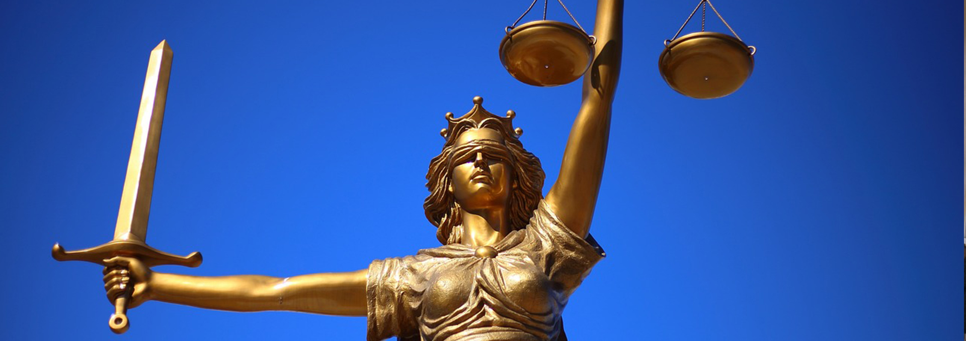 Eine goldene Statue halt einen Schwert und eine Waage in der Hand.