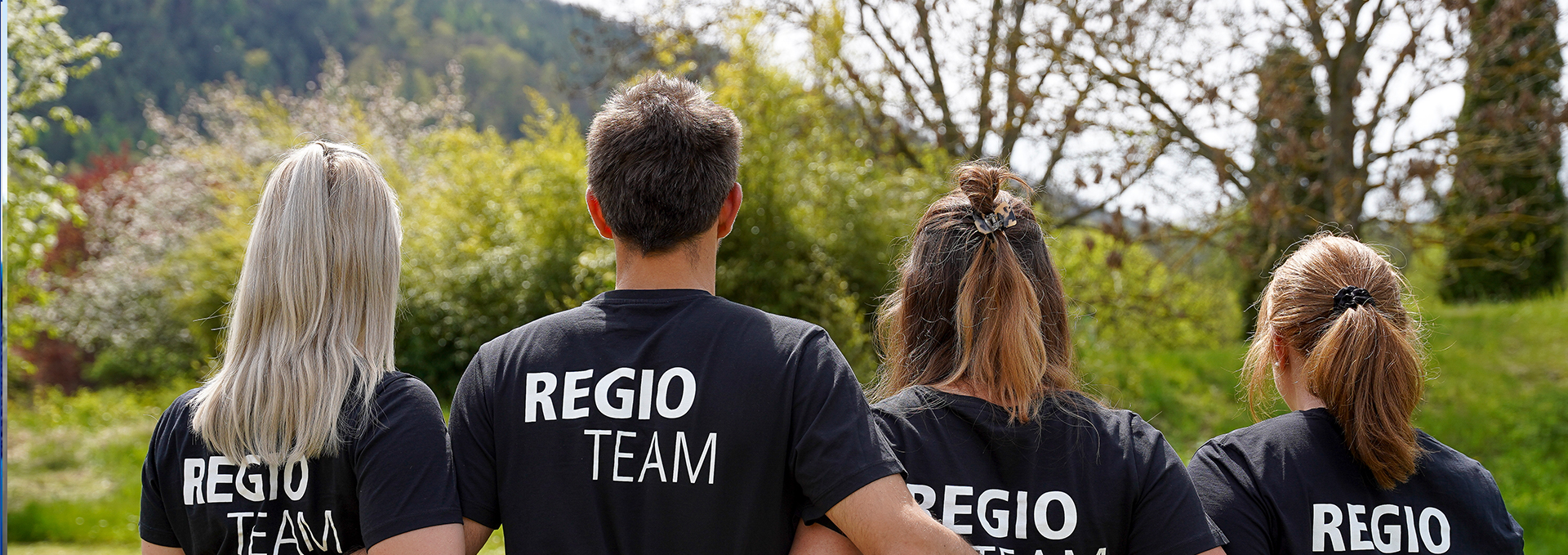 Fünf Personen stehen Arm in Arm, ihre T-Shirts zeigen die Aufschrift "Regio-Team".