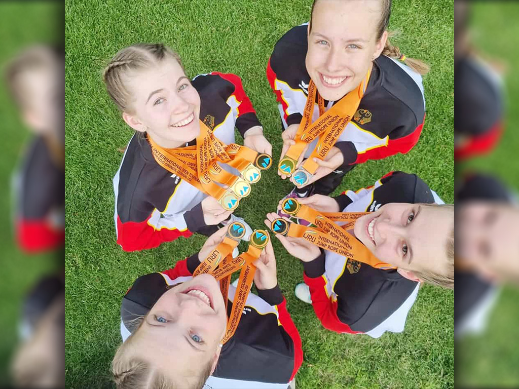 Vier Mädchen präsentieren ihre Medaillen